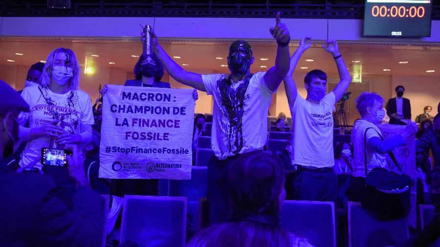 Manifestantes pelo clima protestam durante evento em Paris. Mensagem diz: "Macron: defensor do financiamento dos combustíveis fósseis" - Eric Piermont/AFP