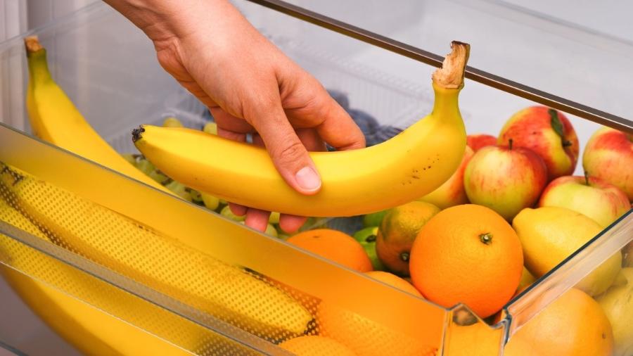 mulher guardando banana; caixa com frutas