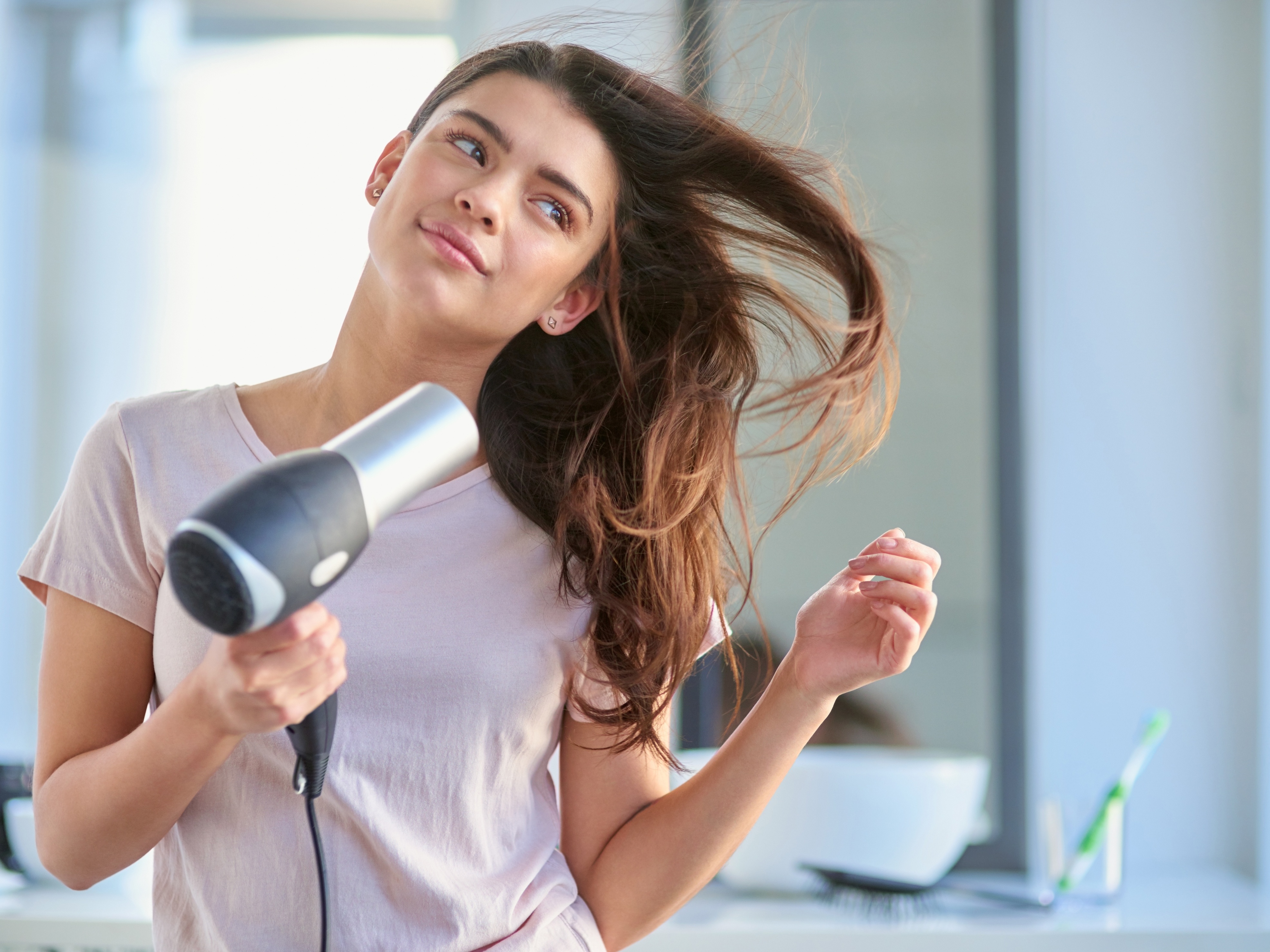 Cabeleireiro seca o cabelo com secador de cabelo para uma mulher