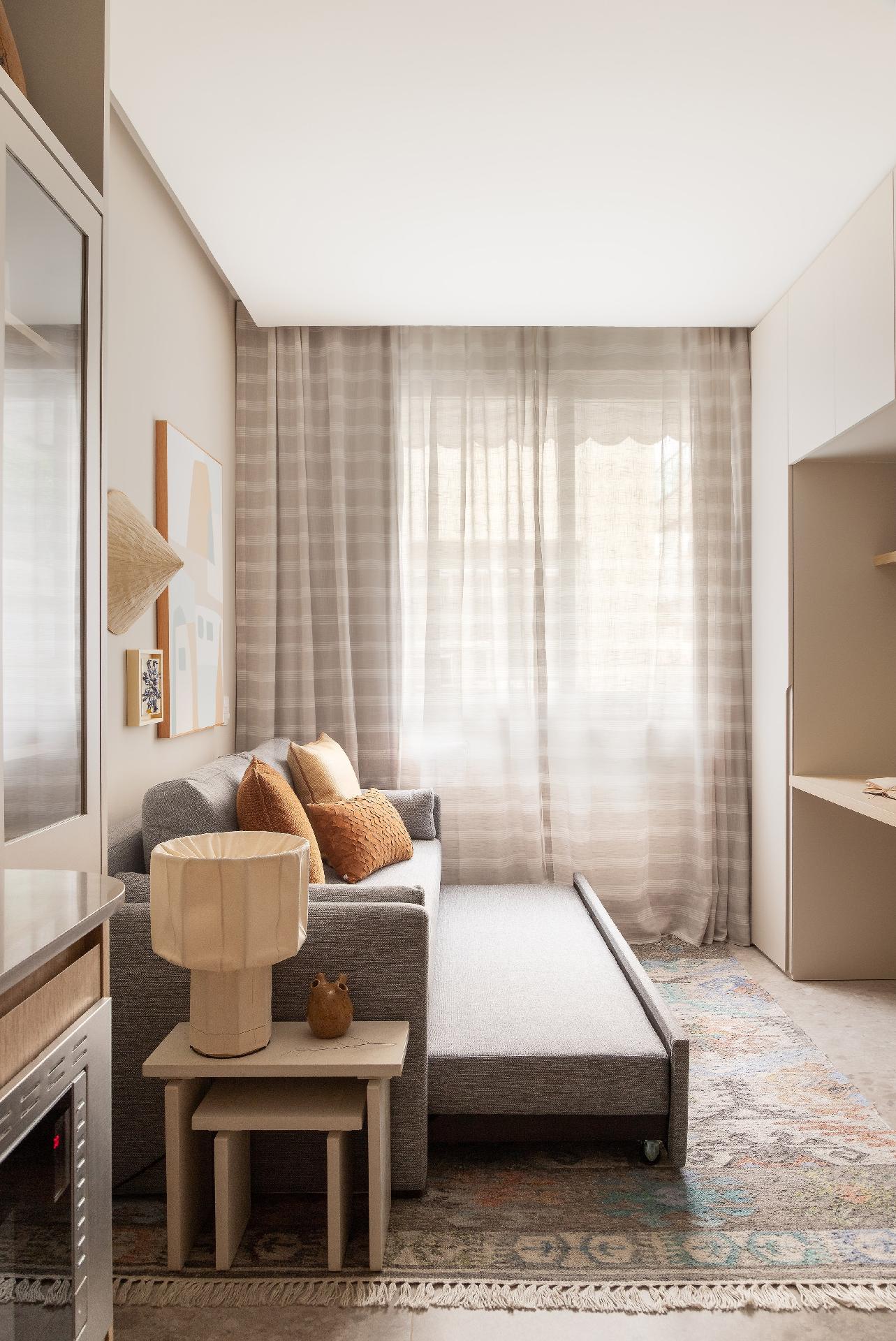 Se você não tem apego com cama, veja essa solução. "Quando está aberto, o sofá-cama fica com as mesmas dimensões de uma cama de casal.  Já os banquinhos também podem ser usados como mesinhas de apoio", exemplifica a arquiteta. - Lilia Mendel/Divulgação