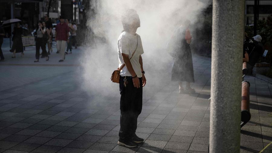 Homem se refesca em dia de calor intenso em Tóquio, no Japão Homem se refesca em dia de calor intenso em Tóquio, no Japão