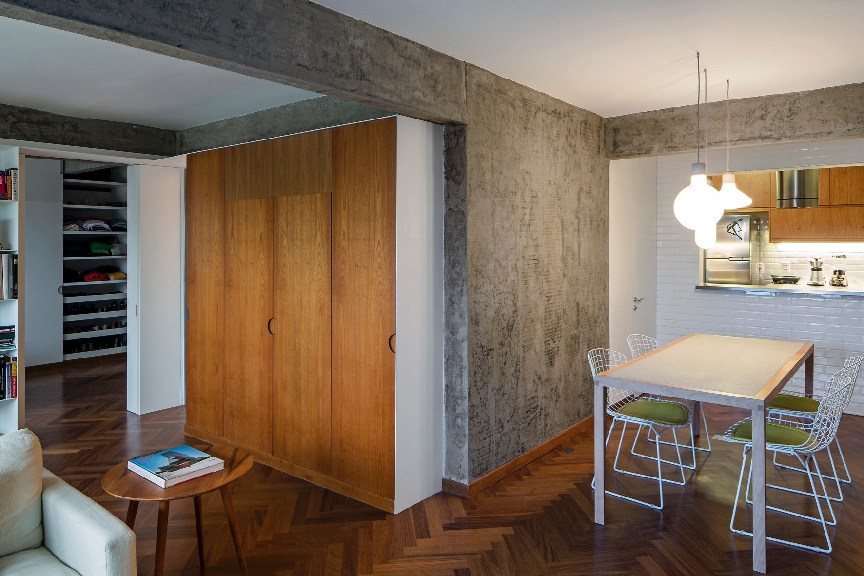 A marcenaria (Marvelar) fica encaixada em estruturas feitas em serralheria com chapas de aço-carbono, pintadas de branco (Dix Arte&Metal). O armário da área social integrada esconde o sistema de refrigeração do Apartameto FT, em São Paulo. Para minimizar os ruídos e deixar a decoração mais "clean" a "caixa" foi desenvolvida pelos arquitetos do escritório Pascali Semerdjian durante a reforma executada em 2014 - Leonardo Finotti/ UOL