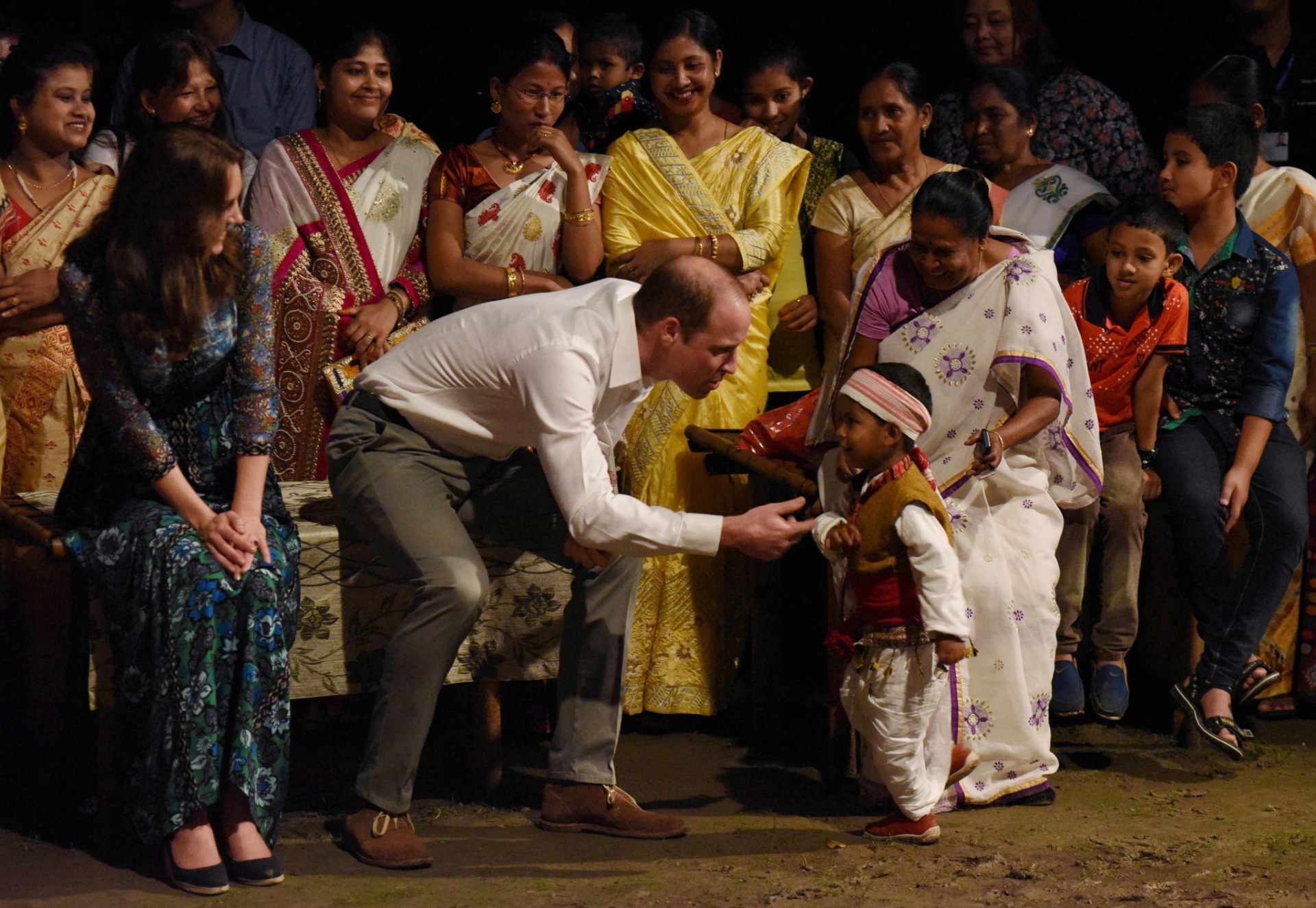 12.abr.2016 - Ao lado de Kate Middleton, príncipe William brinca com criança após assistir a apresentação da dança tradicional Bihu no parque nacional de Kaziranga, na Índia - AFP PHOTO/Biju Boro