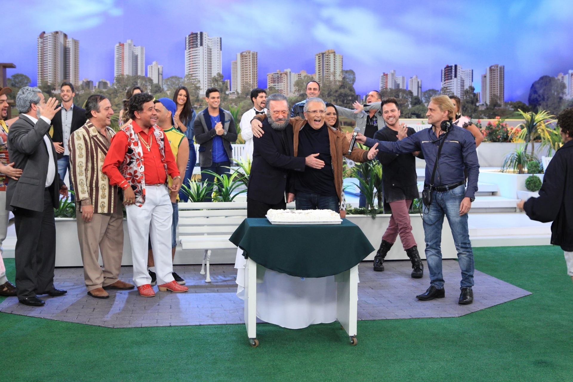A festa surpresa para Moacyr Franco, com direito a bolo, começou após o fim da gravação de "A Praça É Nossa", na última quarta. "É uma honra trabalhar com você, aqui na 'Praça' também todos se sentem honrados", disse Carlos Alberto na homenagem, que irá ao ar na quinta (6), no SBT - Leonardo Nones/SBT