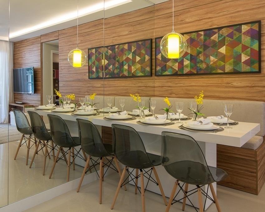 A ideia da arquiteta Giselle Macedo e da designer de interiores Patricia Covolo foi integrar ambientes. Assim, o painel de madeira nas costas da sala de jantar ganha continuidade para o estar. Já o banco na parede é uma solução para áreas reduzidas, pois elimina uma circulação. O quadro com desenho geométrico e a luminária dão um toque de descontração e quebram as cores claras da mesa e do piso - Edson Ferreira/Divulgação