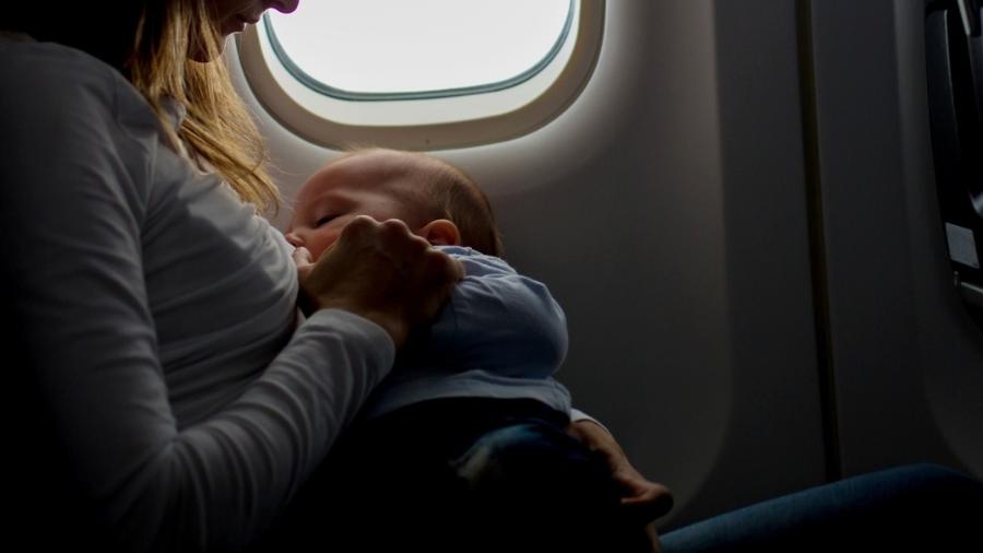 Mulher amamentando no avião - iStock