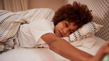 Jovem mulher com sono, deitada, insônia, na cama, dormindo - iStock - iStock