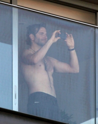 28.mai.2013- Sem camisa, ator Bradley Cooper tira fotos da paisagem do Rio de Janeiro, da sacada do hotel Fasano em Ipanema