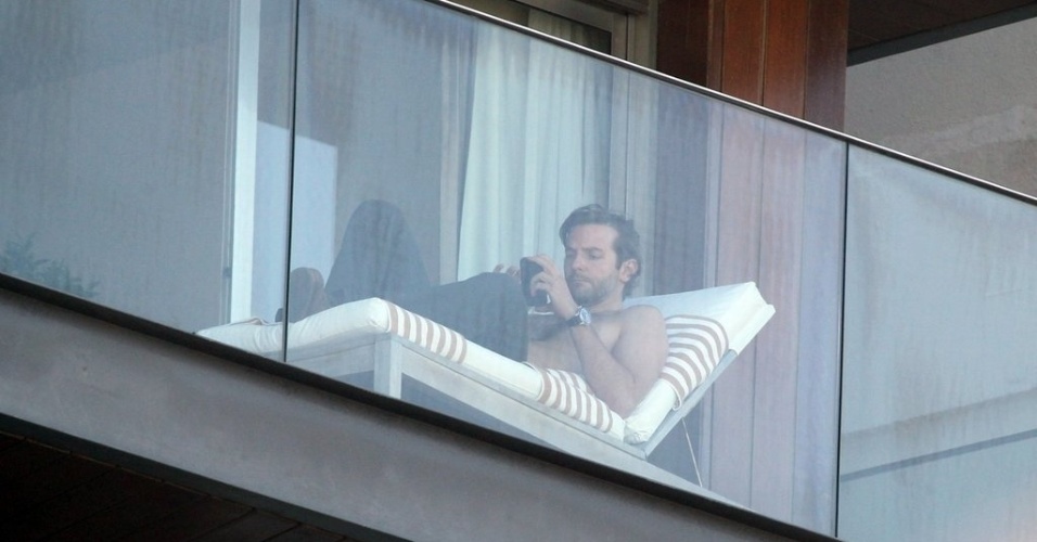 28.mai.2013- Sem camisa, ator Bradley Cooper tira fotos da paisagem do Rio de Janeiro, da sacada do hotel Fasano em Ipanema