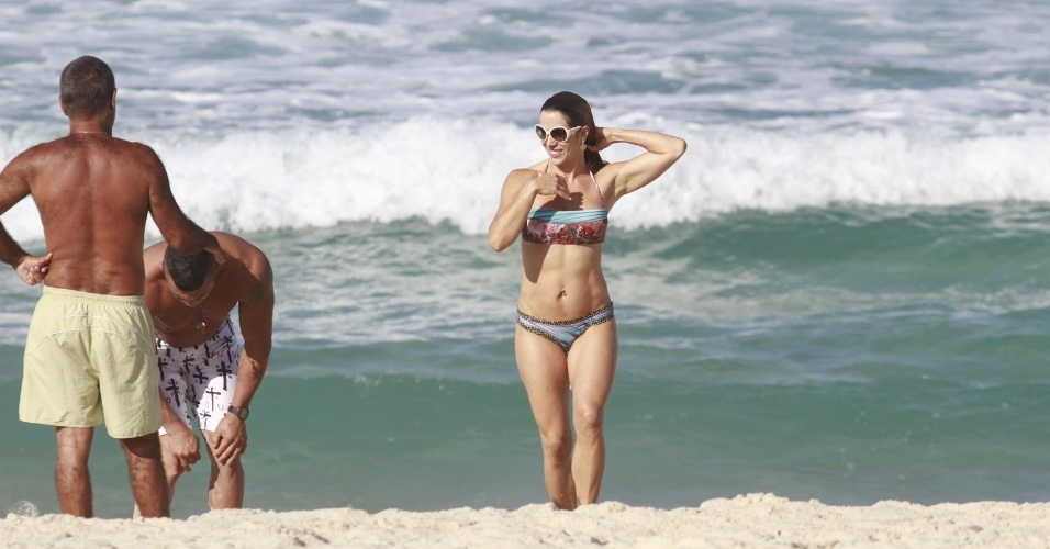 19.jun.2013 - Joana Prado se refresca na praia da Barra da Tijuca, no Rio de Janeiro. A apresentadora está acompanhada do marido, o lutador Vitor Belfort