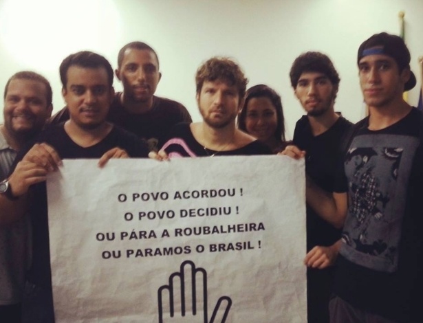 20. jun.2013 - O cantor Saulo Fernandes divulga foto com cartaz de protesto ao lado de amigos