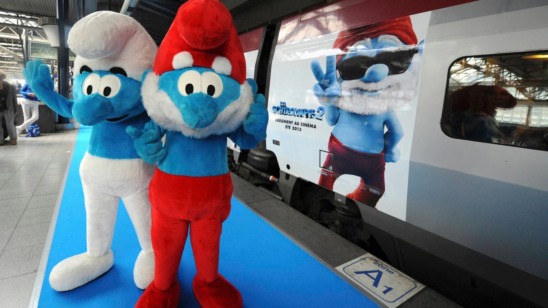 22.jun.2013 - Papai Smurf e outro Smurf posam em frente ao trem decorados com imagens do filme "Smurf 2" no dia em que se comemora o aniversário de seu criador, Peyo, e também o Dia Global dos Smurfs, em Bruxelas, Bélgica - Laurent Dubrule / Reuters