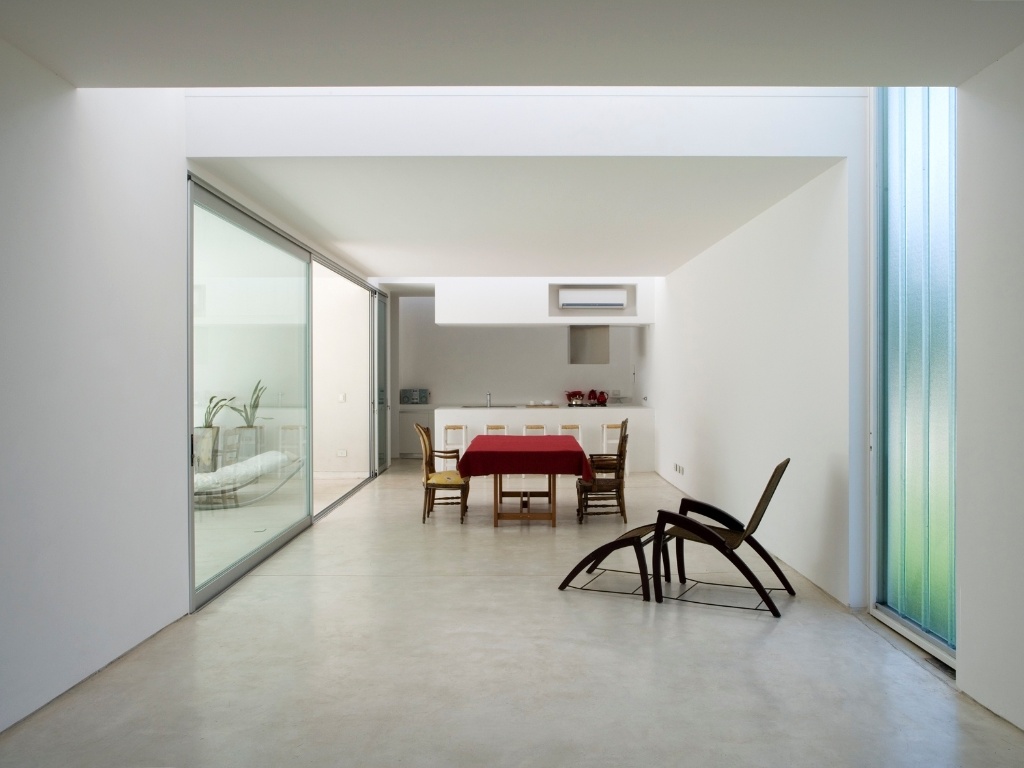 As atividades sociais da Casa Patio se resolvem em um único espaço, setorizado por incidências diversas da luz solar - sempre em função da sua integração com o pátio central. A cozinha fica ao fundo, enquanto a mesa de jantar e o descanso se voltam para o interior aberto, através de porta de vidro corrediças em esquadria de alumínio. As alvenarias levam pintura branca (exterior e interior) e o piso é de cimento polido e resinado. O projeto assinado por Juan Germán Guardati, Román Renzi e Virginia Kahanoff - Leonardo Finotti/ UOL