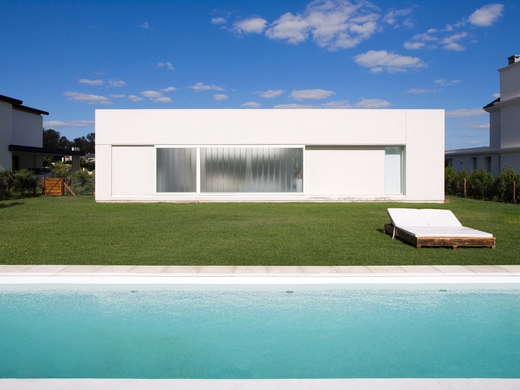 Nos fundos do terreno se encontra o único grande vão em vidro voltado para área externa, delimitando os interiores e o jardim com piscina. O vidro de correr é o mesmo utilizado na porta da frente, autoportante e jateado. A Casa Patio fica em Funes, província argentina de Santa Fe. O projeto é dos arquitetos Juan Germán Guardati, Román Renzi e Virginia Kahanoff - Leonardo Finotti/ UOL