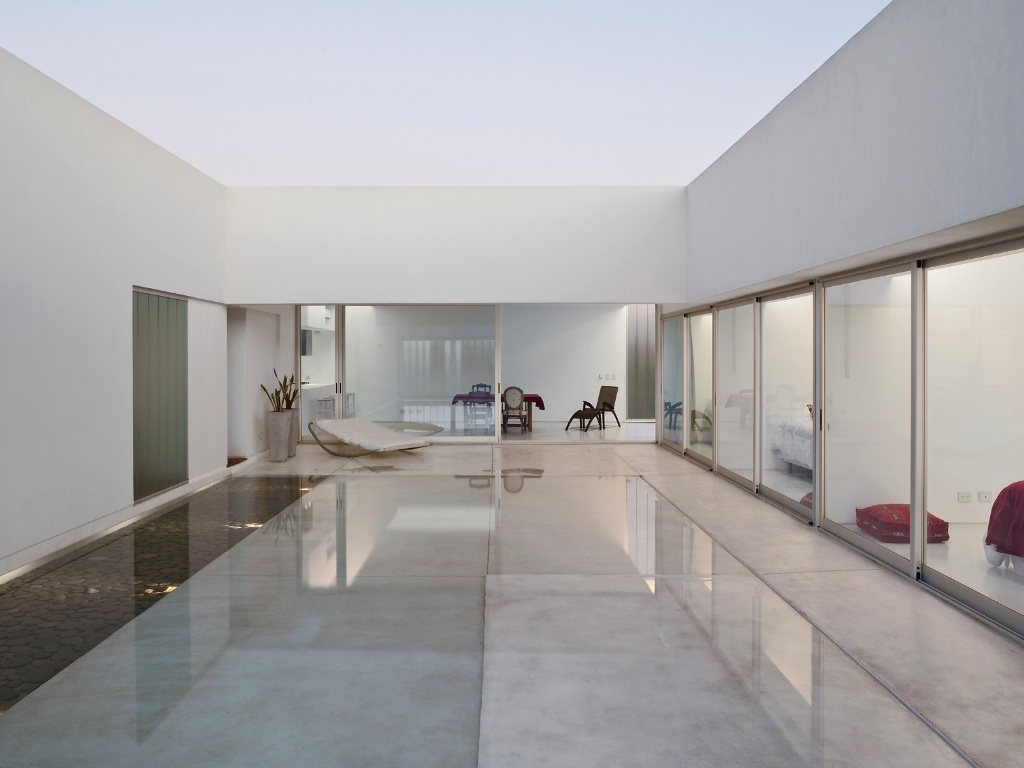 O piso do pátio (cimento polido) tem caimento bem definido e borda perimetral que permitem enchê-lo como um espelho d'água, recurso que ajuda a refrescar altas temperaturas nos dias mais quentes e propagar a luz do sol para dentro dos ambientes. Todos os interiores se comunicam com o pátio através de portas corrediças de vidro (esquadrias de alumínio). A Casa Caja - ou Patio -, tem projeto assinado pelos arquitetos Juan Germán Guardati, Román Renzi e Virginia Kahanoff - Leonardo Finotti/ UOL