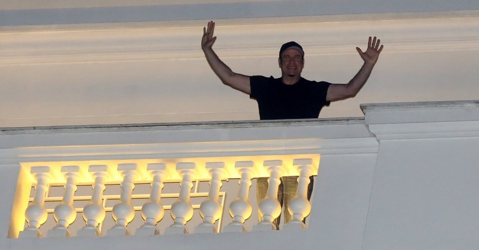 7.jul.20013 - Hospedado no Copacabana Palace, John Travolta acena para fãs da varanda de seu quarto