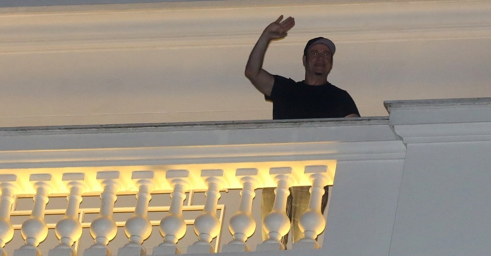 7.jul.20013 - Hospedado no Copacabana Palace, John Travolta acena para fãs da varanda de seu quarto