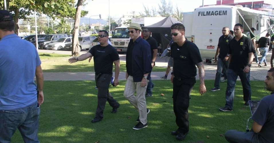 10.jul.2013 - cercado por seguranças e membros da produção, o ator John Travolta anda pelo set de gravação de comercial de cachaça na praia do Recreio dos Bandeirantes, zona oeste do Rio