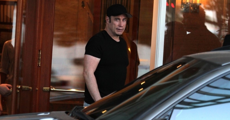 10.jul.2013 - De camiseta e boné pretos, o ator John Travolta deixa o hotel Copacabana Palace e vai para um heliponto também na zona sul do Rio de Janeiro