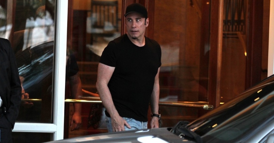10.jul.2013 - De camiseta e boné pretos, o ator John Travolta deixa o hotel Copacabana Palace e vai para um heliponto também na zona sul do Rio de Janeiro