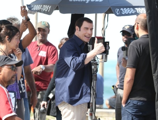 10.jul.2013 - John Travolta faz sinal de "joia" para fãs durante intervalo de gravação de comercial de cachaça no Recreio dos Bandeirantes, no Rio de Janeiro
