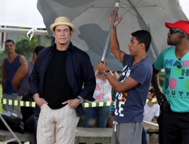 10.jul.2013 - O ator John Travolta caminha no Recreio dos Bandeirantes, no Rio de Janeiro, acompanhado de funcionário que carrega guarda-sol para ele