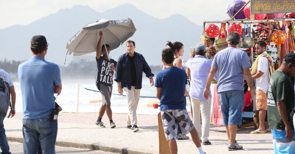 10.jul.2013 - O ator John Travolta caminha no Recreio dos Bandeirantes, no Rio de Janeiro, acompanhado de funcionário que carrega guarda-sol para ele