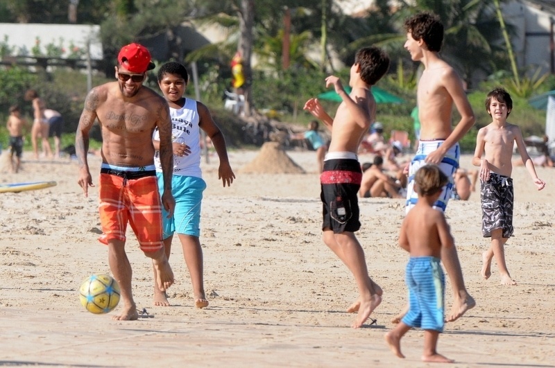 11.jul.2013 -  De férias, Daniel Alves joga bola com crianças na praia de Búzios, na Região dos Lagos, no Rio de Janeiro