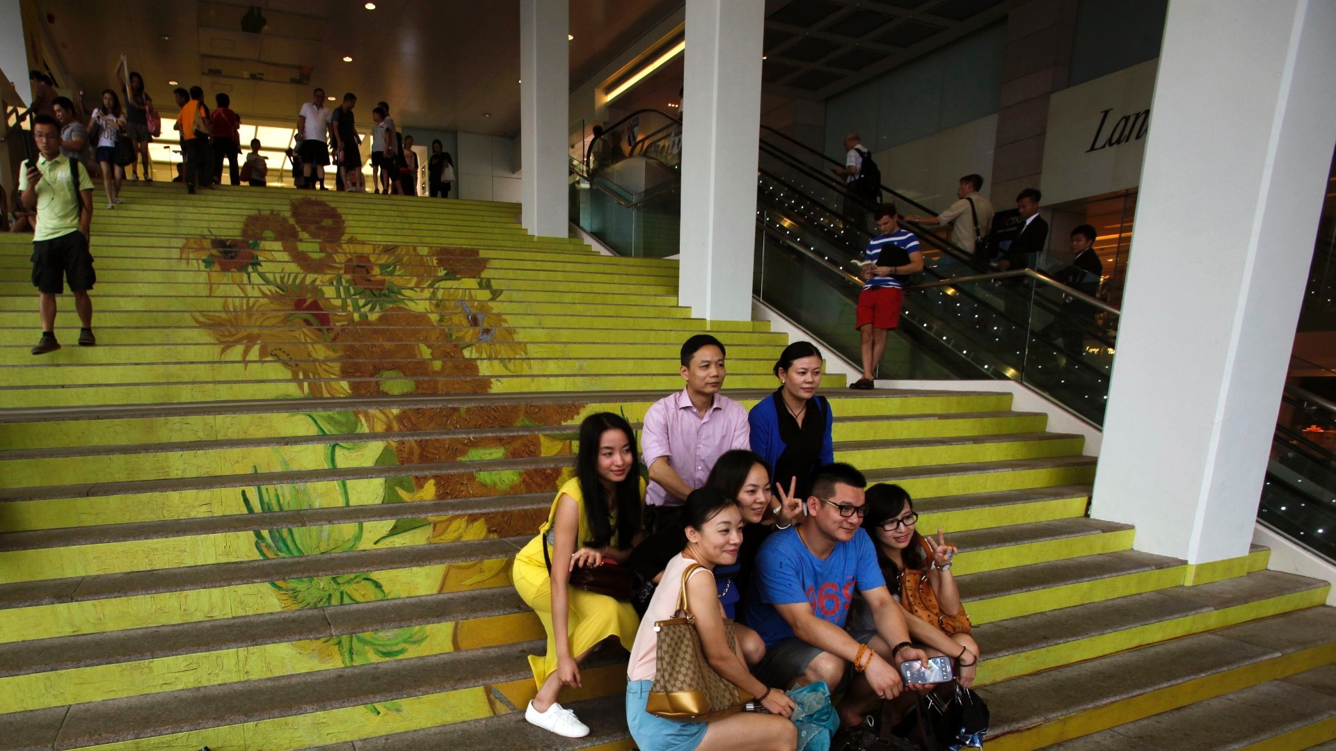 15.jul.2013 - Grupo posa em escadaria com reprodução de "Os Girassóis", de Van Gogh, em Hong Kong.  Criada em conjunto com o Museu Van Gogh, em Amsterdã, a coleção tem reproduções de quadros do artista com alta qualidade e da forma mais fiel possível. A mostra tem, além de "Os Girassóis", obras como "Amendoeira em Flor" e "Boulevard de Clichy". Montada em um shopping na zona portuária, a exposição vai até o dia 4 de agosto - Bobby Yip/Reuters