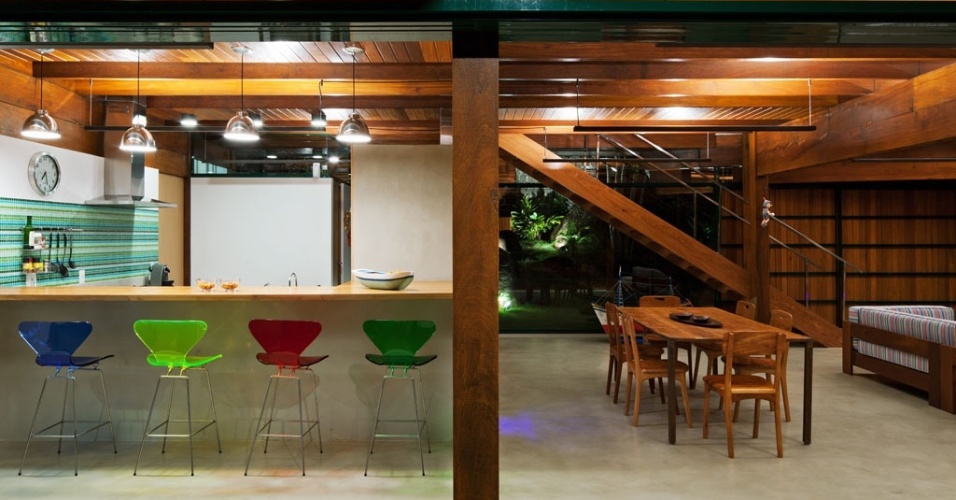 Os espaços interligados da área social, no térreo, permitem a reunião de amigos e familiares em torno do bar e do espaço gourmet. Destaque para as vigas, pilares e escada estruturados em madeira cumaru. A Casa Embaúba foi projetada pela arquiteta Flavia Cancian e está localizada em Ilhabela, litoral paulista - Nelson Kon/ UOL