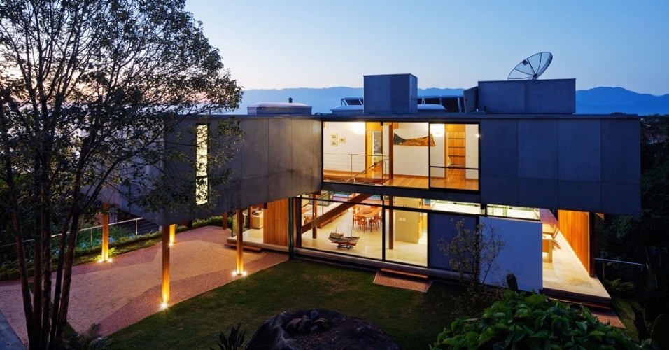 Quando o sol se põe, a Casa Embaúba se ilumina para brindar a noite. Projetada pela arquiteta Flavia Cancian, a residência recebeu muitas arandelas e spots internos e presos ao forro, visíveis graças ao fechamento em vidro que concede transparência ao conjunto - Nelson Kon/ UOL