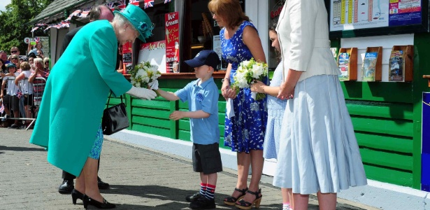 17.jul.2013 - Rainha Elizabeth 2ª recebe flores de Daniel Dixon, de seis anos, no píer Bowness-on-Windermere, em Cumbria, Inglaterra