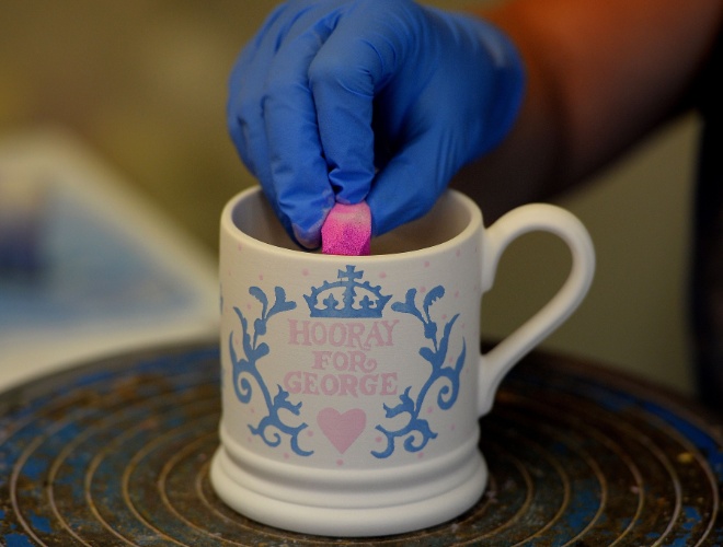 25.jul.2013 - Trabalhadora decora caneca comemorativa pelo nascimento do príncipe de Cambridge, George Alexander Louis, em uma loja de cerâmica em Stoke-on-Trent, Staffordshire, Inglaterra
