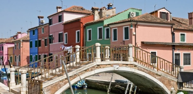 Ponte feita de pedras e tijolos no canal Burano, repleto de casas coloridas - Getty Images
