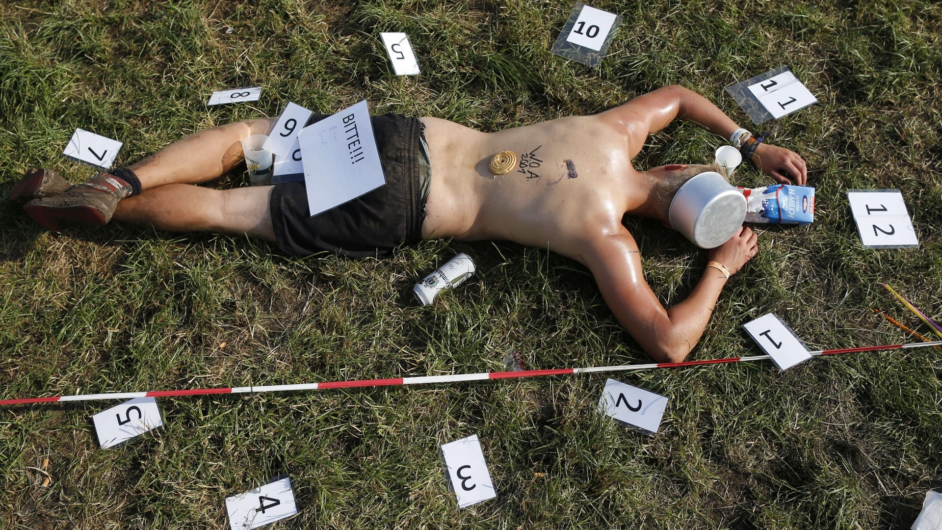 1º.ago.2013 - Fã descansa sobre a grama durante o festival. Folha de papel colocada em cima de seu bumbum diz "Bitte!!!" (por favor, em alemão) - Philipp Guelland/AFP