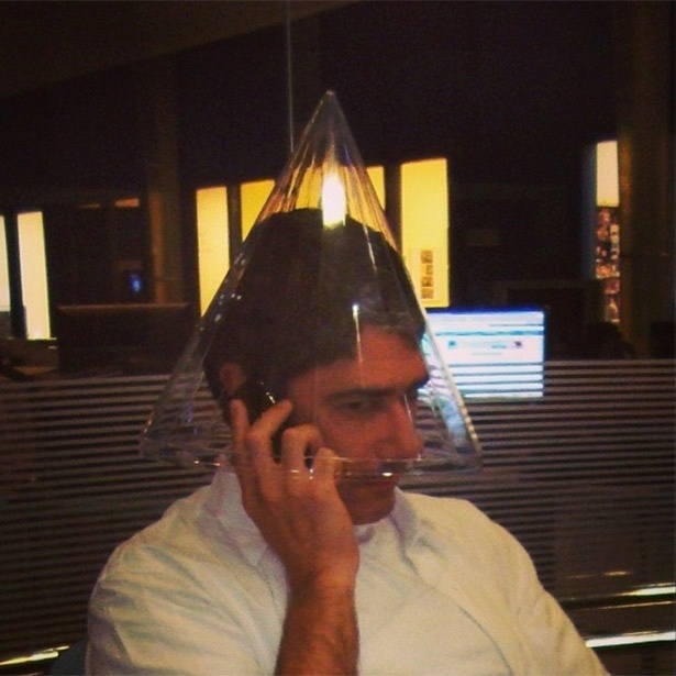 7.ago.2013 - William Bonner fala ao celular usando cone transparente na cabeça.