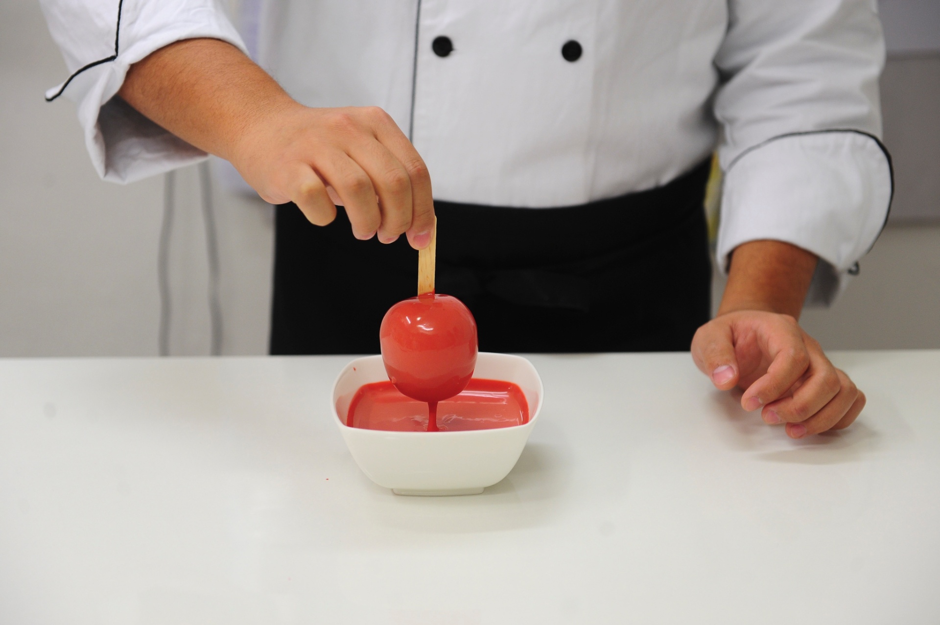 Nesta etapa, o ideal é que a mistura esteja numa tigela de vidro ou cerâmica pequena e funda, de modo que, ao mergulhar a maçã, a fruta fique totalmente submersa. Retire imediatamente a maçã depois de banhá-la no chocolate. Esse é o segredo para que a cobertura fique lisinha e uniforme - Junior Lago/UOL