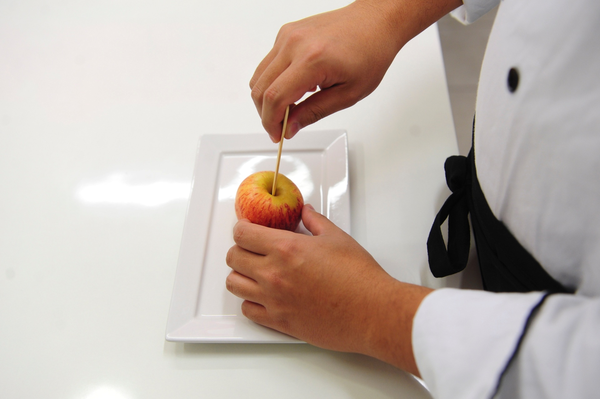 Retire o talo da maçã. Então, segure firmemente a fruta com uma mão enquanto enfia o palito de sorvete com a outra. Faça devagar e com cuidado, para não ficar torto. Reserve - Junior Lago/UOL