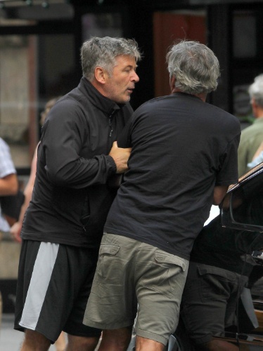 27.ago.2013 - Alec Baldwin agarra o braço do paparazzo que o seguia enquanto ele passeava com a mulher, Hilaria, que deu à luz há menos de uma semana