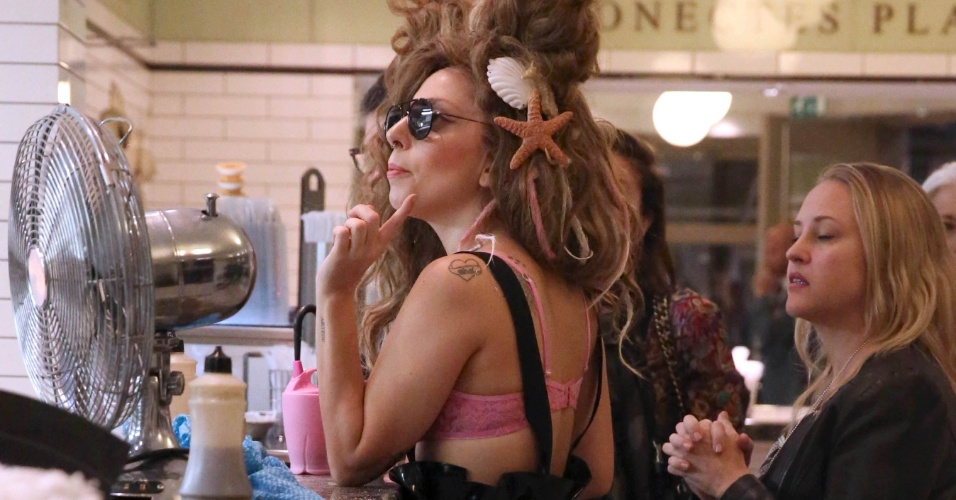 27.ago.2013 - Lady Gaga aguarda pedido em lanchonete de "fish and chips" em Londres. A cantora estava usando um macacão de látex preto e um top rosa transparente, que deixava seus seios à mostra. Na última segunda-feira (26), ela já havia exibido em Nova York um figurino ousado, no qual era possível ver seu bumbum