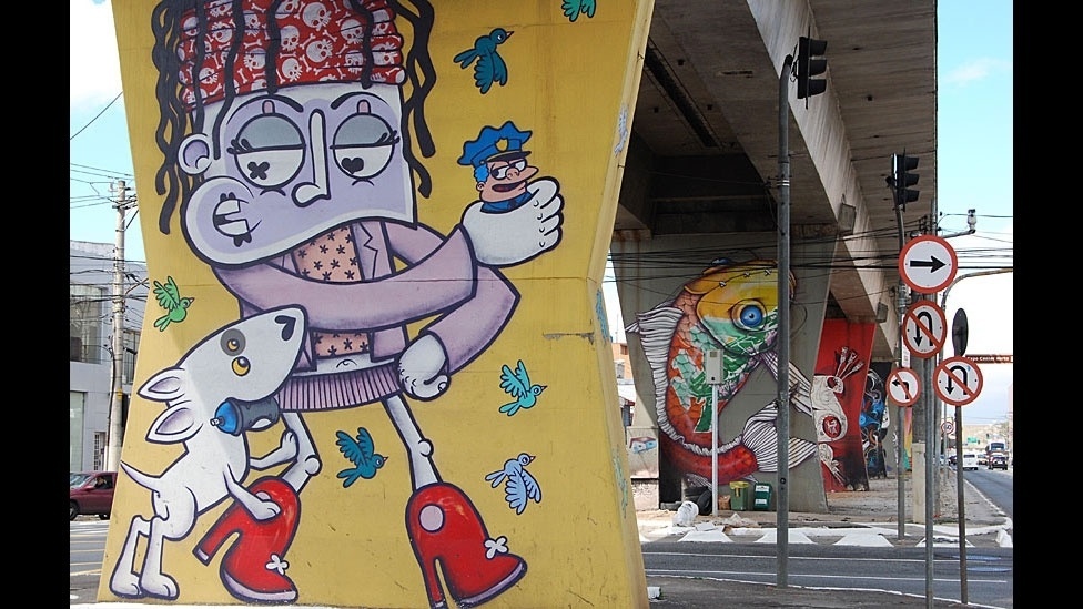 Grafites de Chivitz (primeiro plano) e Binho Ribeiro colorem as pilastras do Metrô na avenida Cruzeiro do Sul, em Santana, São Paulo - Flávia Nogueira/BBC Brasil