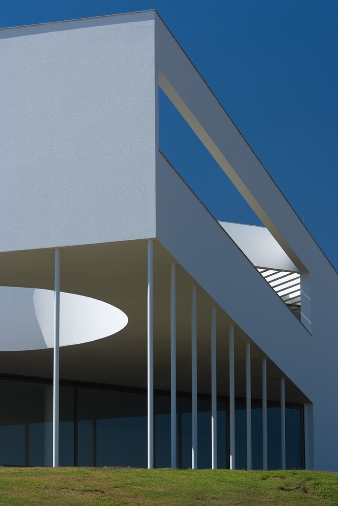 A Casa Galeria, assinada pela MACh Arquitetos, é composta de um bloco retangular longitudinal, paralelo à via de acesso, que dá base a um volume triangular elevado do solo, sustentado pela sucessão de delgados pilares metálicos preenchidos por concreto. A própria sobreposição de volumes geométricos e recortes de vãos, que criam jogos de luz natural e integram os interiores ao entorno, faz do design obra de arte - Fábio Del Re & Carlos Stein/ Divulgação