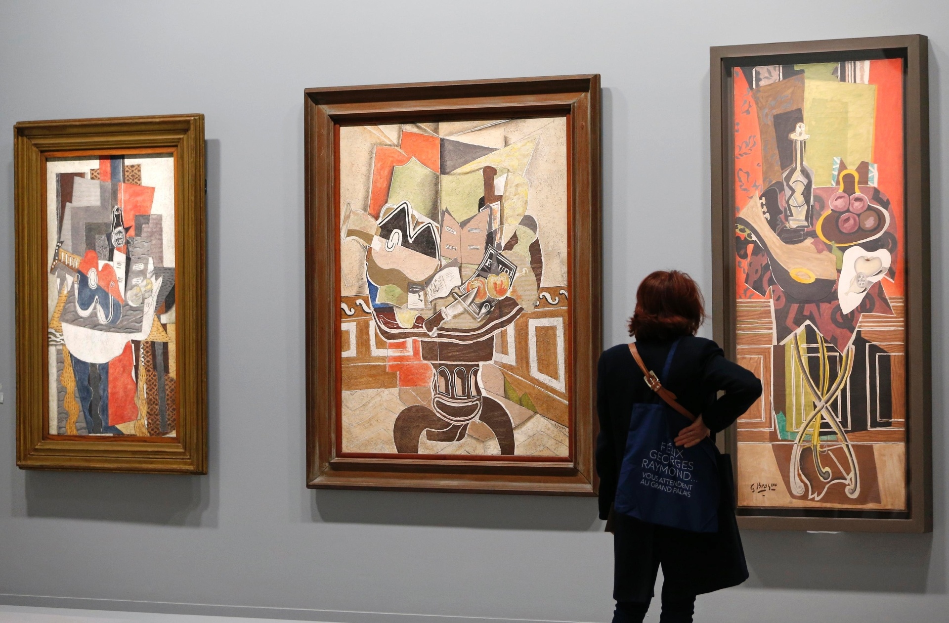17.set.2013 - Visitante olha as pinturas "Le Gueridon Rouge" (1939-1952), "La Table Ronde" (1929) e "Guitare et bouteille de marc sur une table" (1930) do artista francês Georges Braque (1882-1963) na retrospectiva em exibição no Grand Palais Museum, em Paris - REUTERS/Charles Platiau