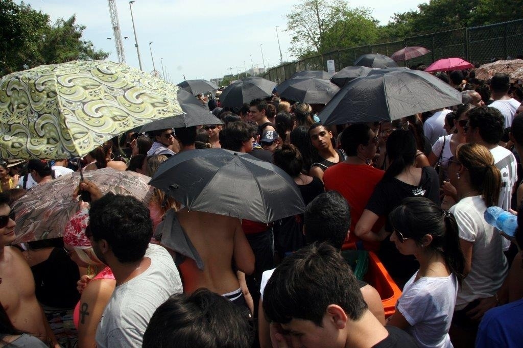 20.set.2013 - Fãs se protegem do sol com guarda-chuvas enquanto aguardam abertura dos portões da Cidade do Rock - Zulmair Rocha/UOL