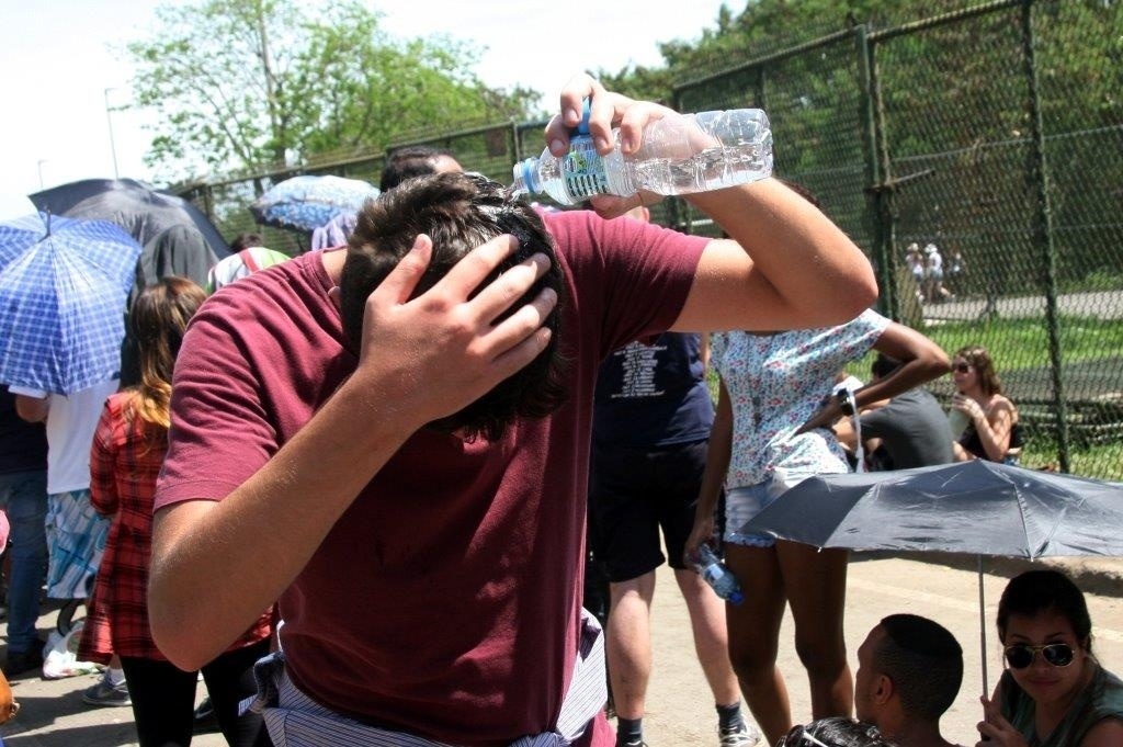 21.set.2013 - Rapaz usa garrafa d´água para se refrescar na fila do 6º dia do Rock in Rio - Zulmair Rocha/UOL