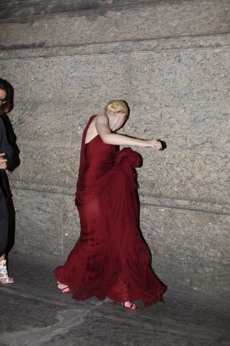 28.set.2013 - Com seu vestido de gala, a atriz Dakota Fanning saiu da exibição do filme "Night Moves" no Festival do Rio e foi a pé para um restaurante no centro do Rio. A atriz teve dificuldade em andar nas ruas com seu vestido longo. Durante o passeio, ela posou para fotos com alguns fãs