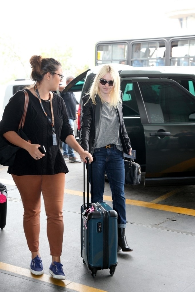 29.set.2013 - Dakota Fanning carrega a própria bagagem no aeroporto internacional do Rio. A atriz veio à cidade para divulgar o filme "Night Moves" no Festival do Rio