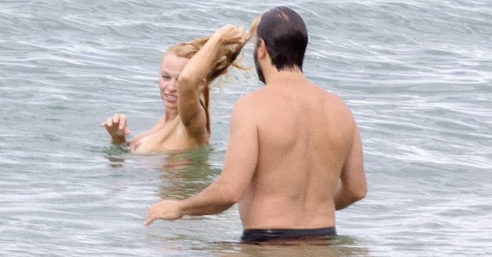 2.ou.2013 - De topless, Pamela Anderson curte praia em Biarritz, na França, com o namorado, Rick Solomon.