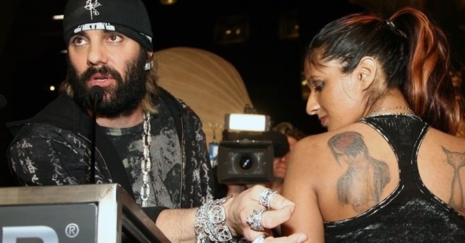 O ilusionista Criss Angel mostra a tatuagem de sua fã Amber Khan, que tatuou o rosto do mágico nas costas, durante o evento 2008 Merlin Award, em Las Vegas (14/2/2008).