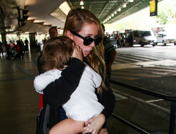 25.out.2013 - Mulher tenta esconder o rosto de Luna, filha da atriz Uma Thurman, que desembarcou com a menina no aeroporto de Guarulhos, em São Paulo